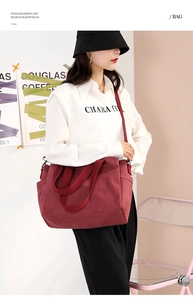Detail of burgundy canvas tote bag featuring adjustable shoulder strap and side pocket