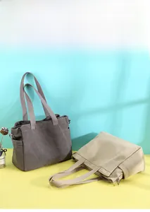 Detail view of durable canvas tote bags in grey and beige with side metal D-rings