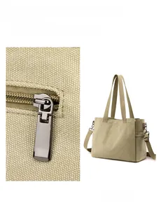 Detail of durable gun-grey metal zipper and khaki canvas tote bag with adjustable strap