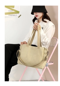 Close-up of beige canvas tote bag with adjustable strap and side pocket detail