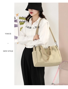 Minimalist beige canvas tote bag shown worn as a shoulder bag on a female model