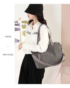 Detail view of a large grey canvas tote bag with dual straps worn by a fashion model
