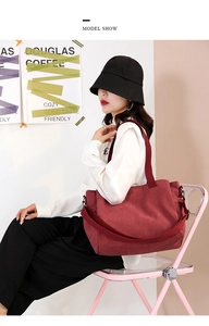 Model wearing a burgundy large canvas tote bag with a matching wide strap for daily use