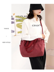 Detail of burgundy canvas tote bag with adjustable strap and practical side pockets