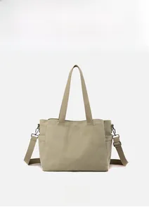 Detail view of khaki canvas tote with adjustable strap and vintage bronze hardware