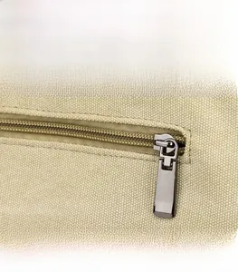 Detail shot of a smooth gunmetal zipper on high-quality beige canvas tote bag fabric