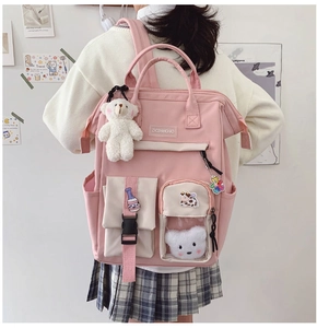 Pink student backpack with cute plush bear charms and multiple functional pockets on the back