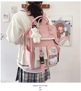 Detail view of pink student backpack featuring plush bear pendant and cute embroidery patches