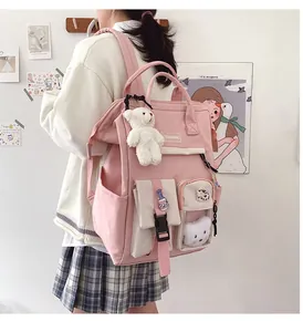 Detail of pink student backpack with bear pendant and cute embroidery in casual style