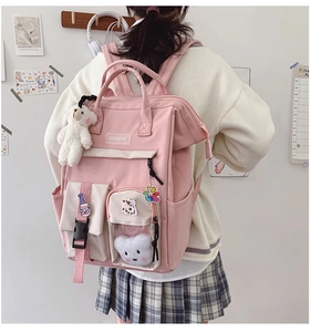 Detail view of pink student backpack with cute bear pendant and creative decorative patches