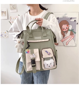Detail of green nylon backpack featuring cute bear charms and multiple utility pockets