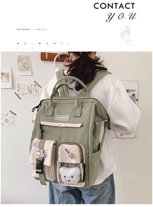Sage green nylon backpack with cartoon patches and plush bear charm worn by a model