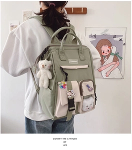 Close-up of green waterproof nylon backpack with multi-pocket design and cute bear pendant