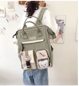 Detail of green and beige nylon school backpack with cute cartoon badges and plush bear head