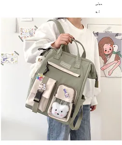 Detail of green and beige multi-pocket school backpack with cute bear charm and badges