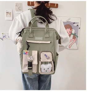 Detail view of a green canvas backpack with plush bear charms and multi-pocket design