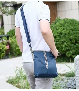 Close-up of small navy oxford shoulder bag showing texture and adjustable strap in outdoor use