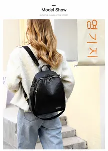 Vista trasera de mochila de cuero negro con cremalleras plateadas sobre una modelo