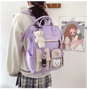 Close-up of lavender nylon school backpack with plush bear pendant and cute badges