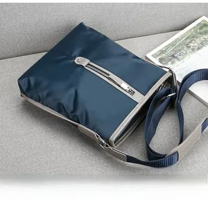 Close-up of a blue waterproof oxford nylon crossbody bag resting on a grey fabric sofa
