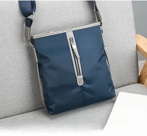 Detail of dark blue nylon men's crossbody bag with vertical zipper on a fabric sofa