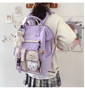 Detail view of large purple student backpack with plush charms and functional pockets