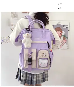 Detail of purple and beige campus backpack with cute badges and plush bear charm