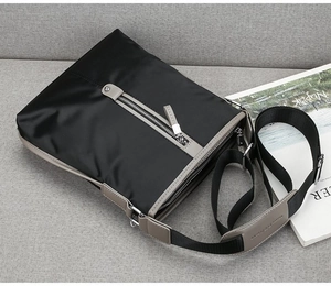 Detail view of water-resistant oxford messenger bag with gray zipper pocket on sofa