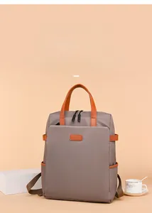 Dettaglio dello zaino grigio impermeabile con finiture in pelle arancione e tasca frontale