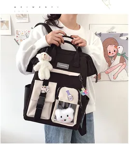 Detail of black and white school backpack featuring plush bear and decorative badges