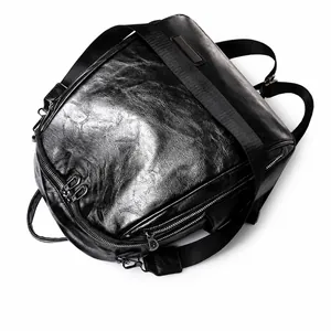 Vista detallada superior de mochila negra en cuero aceitado con texturas y cremalleras plateadas