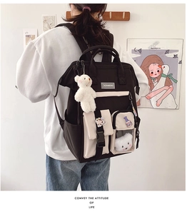 Back view of a large black and beige nylon school backpack with a cute white bear charm