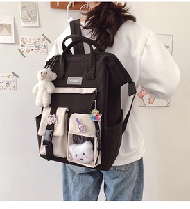 Detailed close-up of a black canvas student backpack with cute plush bear and cow charms
