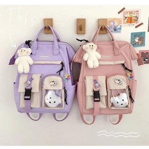 Detail of cute canvas backpacks in pastel purple and pink with bear charms and patches