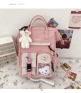 Close-up of pink school backpack featuring cute plush bear charms and multiple pockets