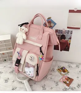 Pink nylon school backpack featuring multiple pockets and cute plush bear charm detail
