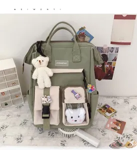 Close-up of light green canvas backpack with cute plush bear and cartoon badges decor