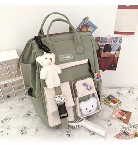 Detail of sage green school backpack with plush bear charms and transparent pocket