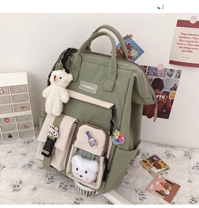 Detail of multi-pocket nylon backpack in sage green and beige with plush bear charm