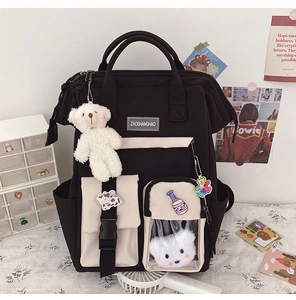Close-up of black and beige canvas backpack featuring cute plush bear and badge details