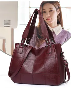 Detail view of burgundy leather tote bag with elegant quilted stitching and side metal hooks
