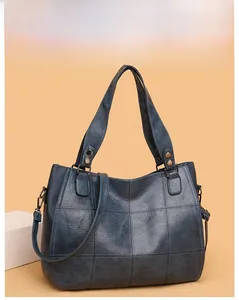 Close-up of navy blue leather tote bag showing square stitching and bronze hardware
