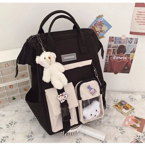 Close-up of black and white student backpack with teddy bear pendant and transparent pocket
