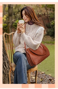 Detail of dark brown patchwork leather handbag with adjustable strap on model