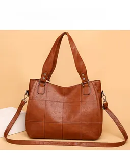 Detail view of brown faux leather bag featuring lattice stitching and metal buckles