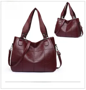 Macro detail of wine red tote bag featuring square quilted stitching and metal rivets
