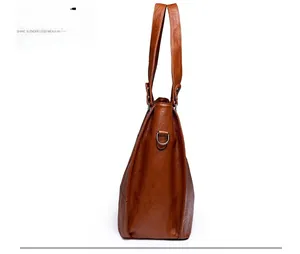 Side view of large brown tote bag showing lychee grain texture and metal D-ring detail