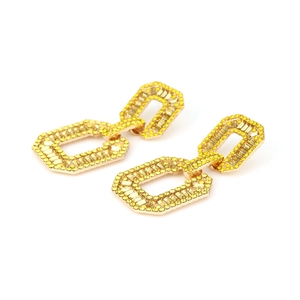Detail of geometric gold earrings featuring pavé yellow crystals in a double rectangular drop
