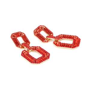 Macro detail of geometric gold alloy earrings with sparkling red rhinestone settings