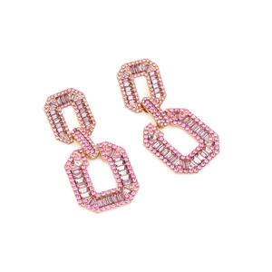 Close-up of geometric gold chain earrings with pink and purple square crystal settings